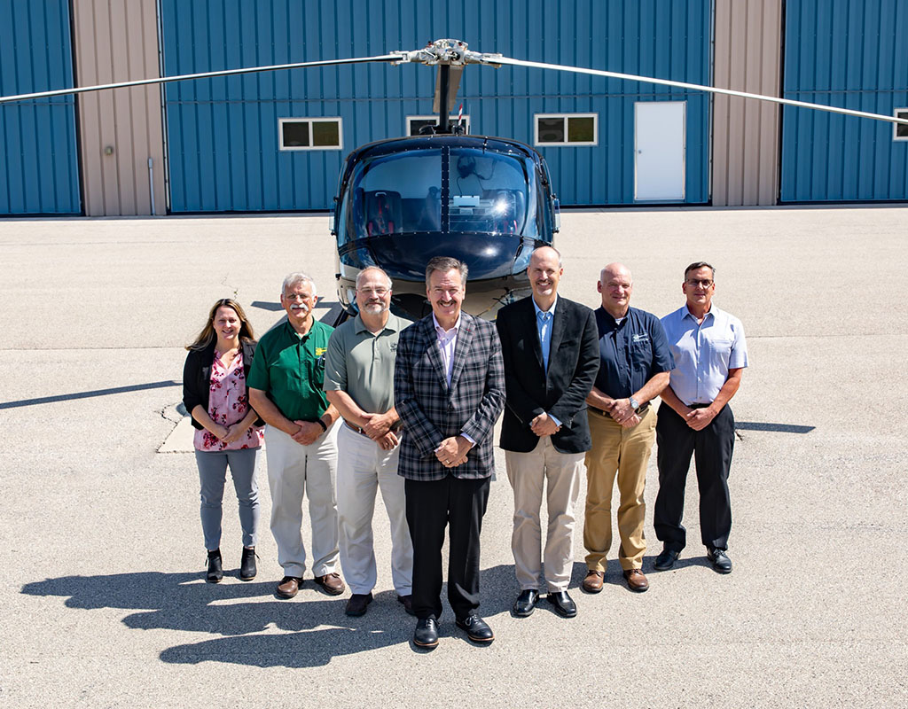 Chuck Surack (center) stands outside the headquarters of Enstrom Helicopter Corp. – the company he dramatically saved from bankruptcy in May. Brent Bundy Photo