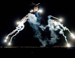 A CH-47 cargo helicopter dispenses countermeasure flares during a training exercise. The Countermeasures and Flares Branch at Picatinny Arsenal strives to increase aircraft survivability through the design, development and production support of countermeasures such as decoys, chaff, and flares that divert enemy missiles. The Branch is part of the U.S. Army Combat Capabilities Development Command (DEVCOM) Armaments Center. Clinton Plaza Photo