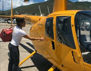 Maria Rodriguez, owner of Caribbean Buzz Helicopters, loads a bag into the company’s Robinson R44, painted its signature yellow. Dan Parsons Photo
