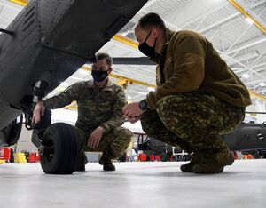 U.S. Army Sgt. Zach Hollman, UH-60 crew chief Company B 147th Aviation Regiment, Michigan Army National Guard (MIARNG), and Latvian Air Force Capt. Raimonds Lugēņins inspect landing gear on a Black Hawk, Dec. 1, 2021, at Grand Ledge, Mich. The MIARNG is providing training for the first Latvian UH-60 maintainer after the country purchased four Black Hawks. Staff Sgt. Tristan D. Viglianco for U.S. Air National Guard Photo