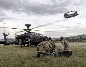 Members of the Army Air Corps, wait to re-arm an Apache helicopter during a FARP (forward arming and refueling point). British Army Photo