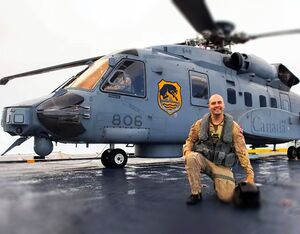 Royal Canadian Air Force Pilot Captain Dan Simpson poses in front of HMCS Vancouver’s CH-148 Cyclone Helicopter Canuck. Sgt. Ghislain Cotton for Canadian Armed Forces Photo