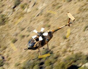 An MD 53F Cayuse Warrior aircraft flies over rural terrain. The ‘Plus’ version of this platform features mission enhancements that include the weapons system, avionics improvements, armor, and increased power performance. MD Helicopters Photo