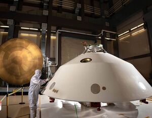 Lockheed Martin engineers work on the construction of the aeroshell for the Mars 2020 mission. The cone-shaped back shell and orange heat shield will protect the Perseverance rover on its way to the surface of Mars. Lockheed Martin Photo